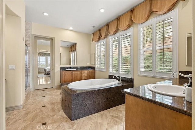 full bath with a garden tub, two vanities, a sink, and recessed lighting