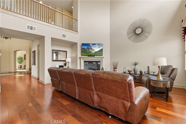 8072 Soft Winds Dr, Corona, CA 92883 - living room with a towering ceiling, arched walkways, wood finished floors, and a glass covered fireplace