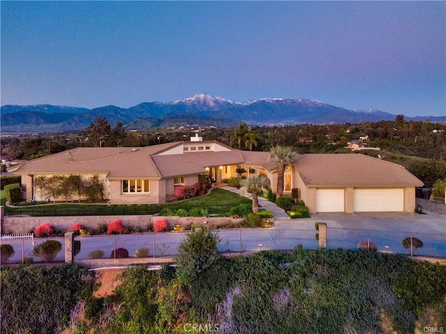 view of front of house with brick siding, an attached garage, a front yard, a mountain view, and driveway