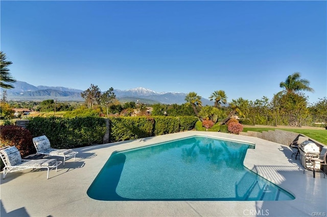 view of pool featuring a patio, a mountain view, and a fenced in pool