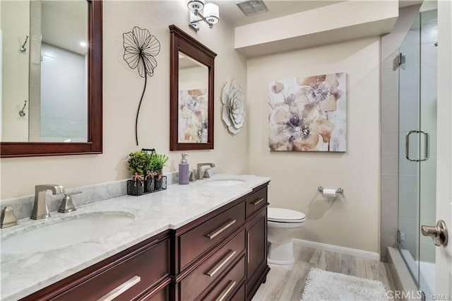 full bathroom with a shower with shower door, a sink, toilet, and wood finished floors