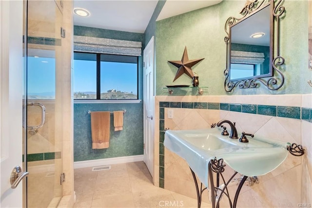 full bath featuring a stall shower, visible vents, a wainscoted wall, tile patterned flooring, and tile walls