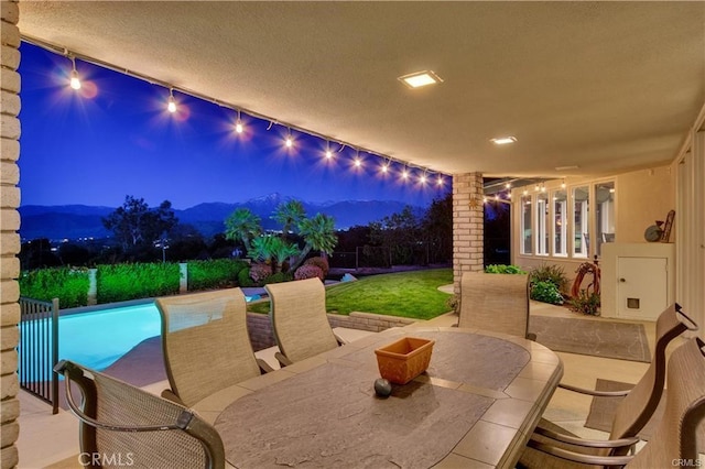 patio at night featuring an outdoor pool, a mountain view, and outdoor lounge area