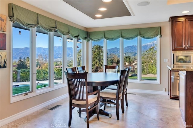 dining room featuring a mountain view, plenty of natural light, visible vents, and baseboards