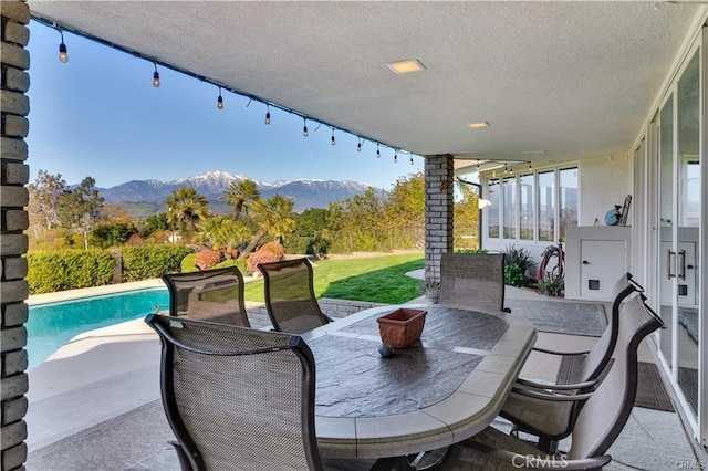 view of patio with a mountain view, an outdoor pool, and outdoor dining space