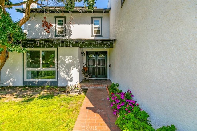 property entrance featuring a lawn and stucco siding