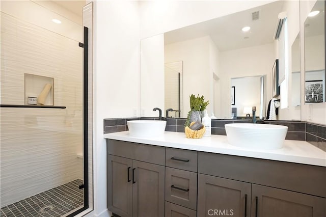 full bath with visible vents, a sink, a shower stall, and double vanity