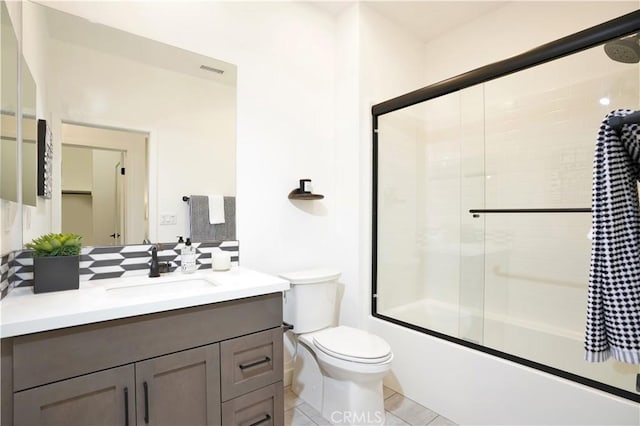 bathroom with visible vents, toilet, tile patterned flooring, combined bath / shower with glass door, and vanity