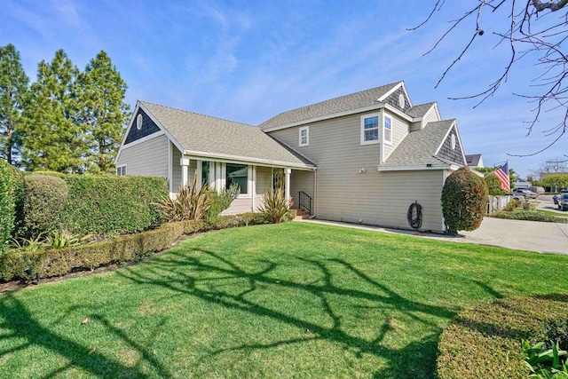 view of front of property featuring roof with shingles and a front yard