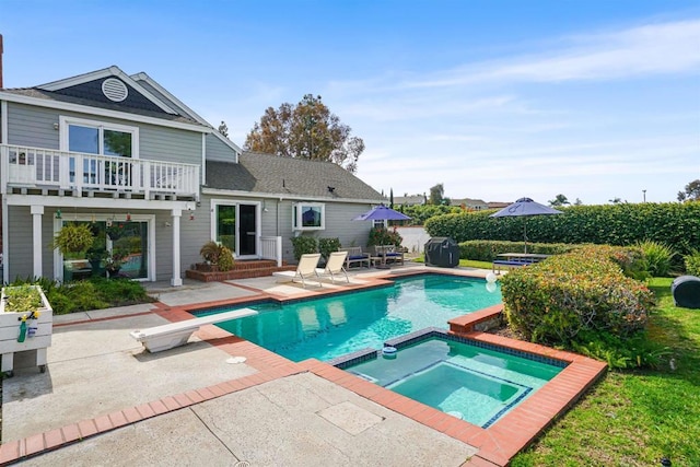 view of swimming pool with a pool with connected hot tub, a patio area, grilling area, and a diving board