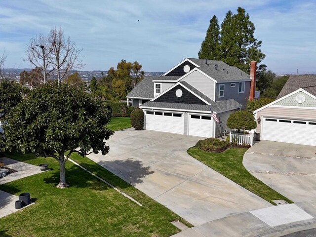 view of front facade with a garage, driveway, a shingled roof, and a front yard