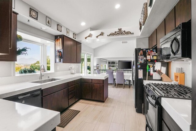 kitchen with black appliances, dark brown cabinets, light countertops, and a sink