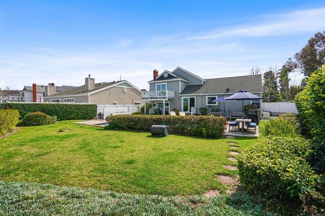 back of property with a patio area, a fenced backyard, a yard, and a balcony