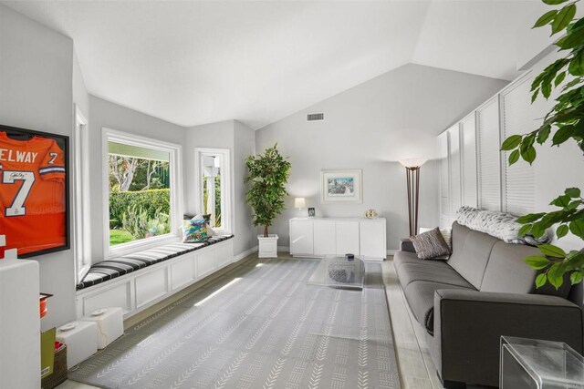 living room featuring baseboards, visible vents, and vaulted ceiling