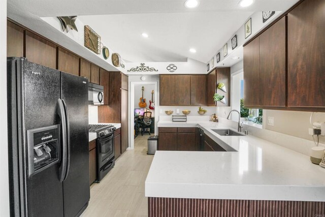 kitchen featuring lofted ceiling, light countertops, a sink, a peninsula, and black appliances