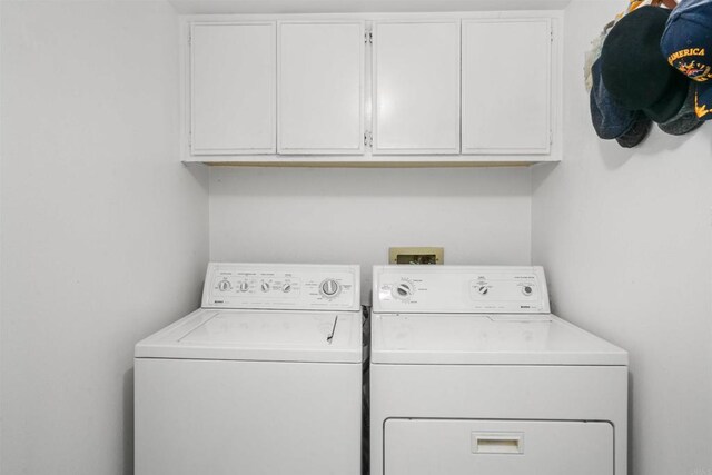 clothes washing area with washing machine and dryer and cabinet space