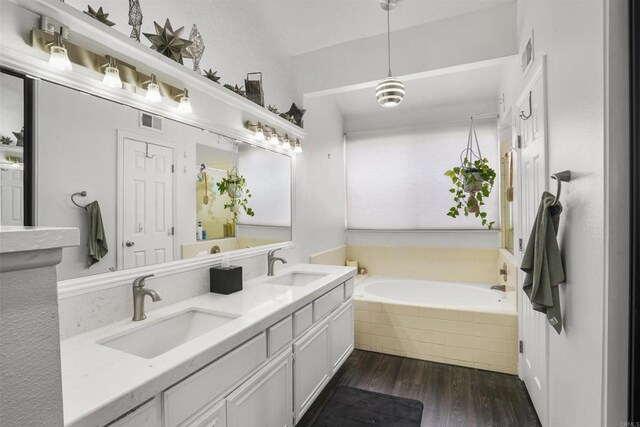 full bath with a garden tub, wood finished floors, a sink, and visible vents