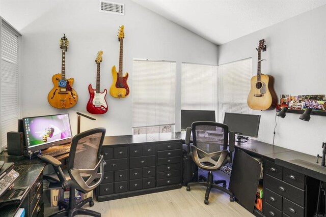 home office with lofted ceiling, visible vents, and wood finished floors