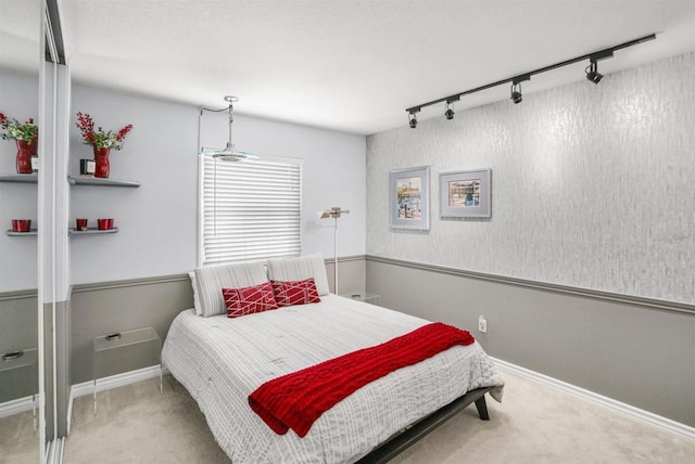 carpeted bedroom with rail lighting and baseboards