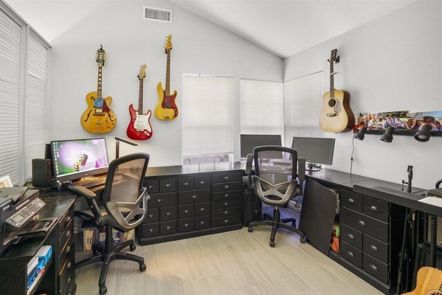 office space featuring vaulted ceiling, wood finished floors, and visible vents