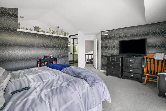 carpeted bedroom featuring an accent wall, visible vents, vaulted ceiling, and wallpapered walls