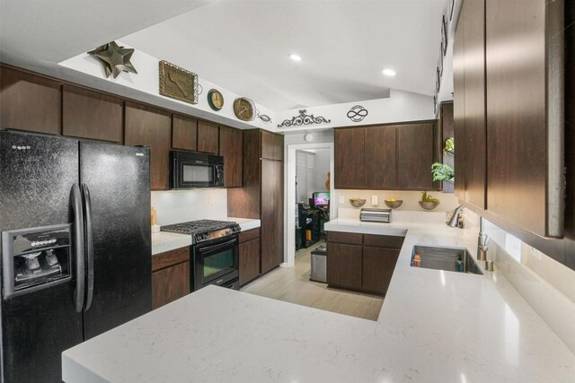 kitchen with dark brown cabinetry, a peninsula, a sink, light wood-type flooring, and black appliances