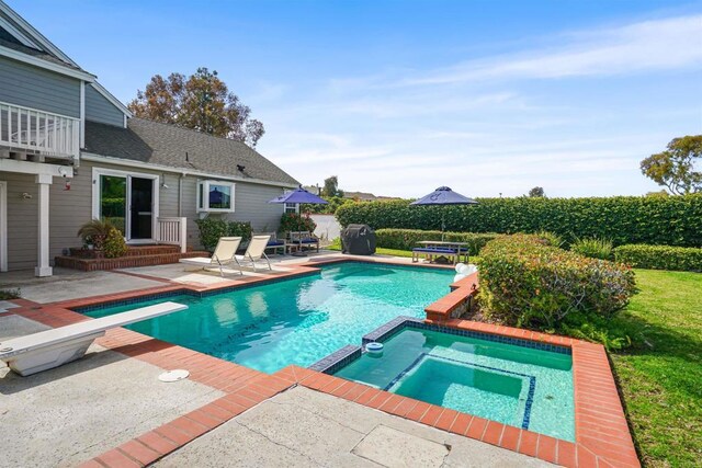 view of swimming pool with a diving board, a patio, and a pool with connected hot tub