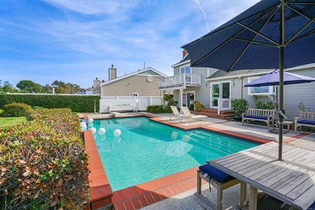 view of swimming pool featuring fence, a diving board, a fenced in pool, and a patio