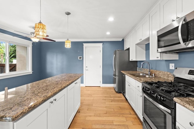 kitchen featuring light wood-style flooring, a sink, appliances with stainless steel finishes, white cabinetry, and crown molding