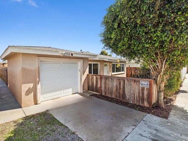 single story home featuring concrete driveway, fence, and stucco siding