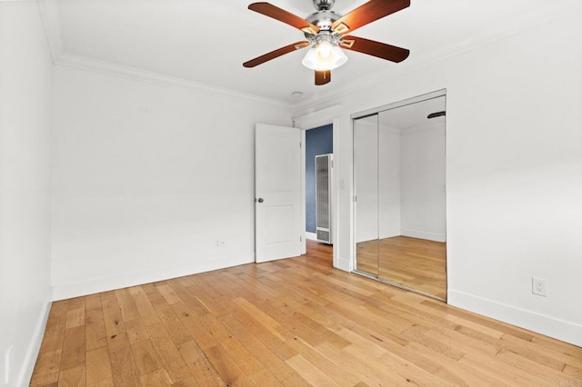 unfurnished bedroom featuring light wood-style floors, baseboards, a closet, and ornamental molding