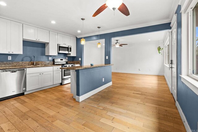 kitchen featuring a ceiling fan, a sink, white cabinets, light wood-style floors, and appliances with stainless steel finishes