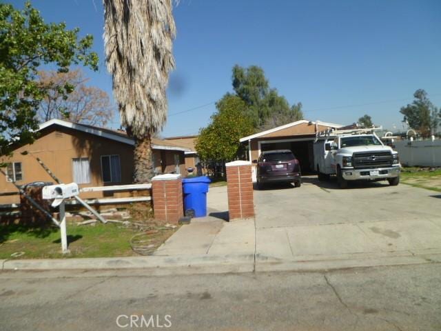 view of front of house with concrete driveway, a carport, and fence