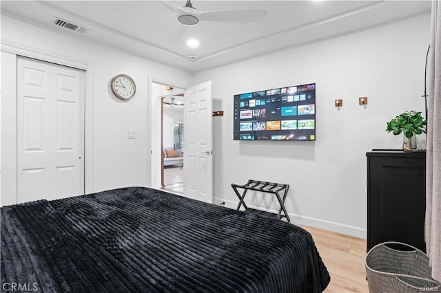 bedroom with ceiling fan, wood finished floors, visible vents, baseboards, and a closet