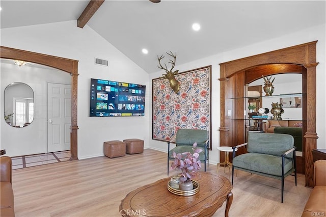 interior space featuring baseboards, visible vents, arched walkways, wood finished floors, and vaulted ceiling with beams