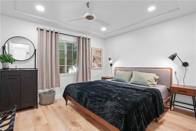 bedroom featuring ceiling fan, a tray ceiling, recessed lighting, and light wood-style floors