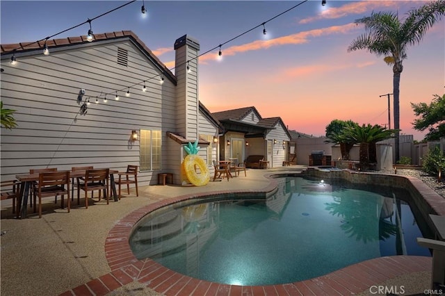 view of pool featuring outdoor dining space, a pool with connected hot tub, a patio area, and a fenced backyard