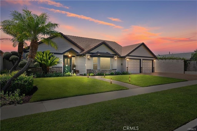 craftsman-style house featuring driveway, a lawn, a tiled roof, an attached garage, and fence