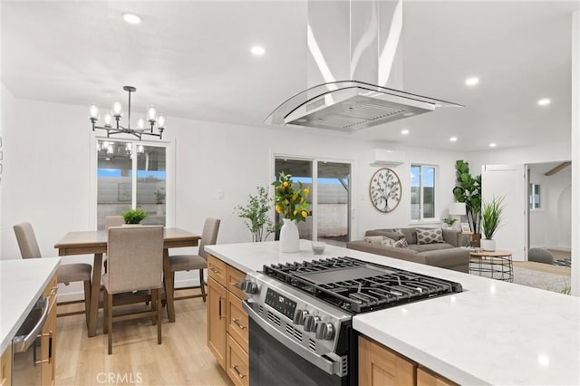 kitchen with light wood-style flooring, stainless steel gas range, range hood, a notable chandelier, and a wall mounted AC