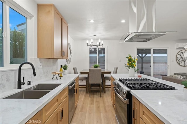 kitchen with island range hood, stainless steel appliances, a sink, light wood-style floors, and decorative backsplash