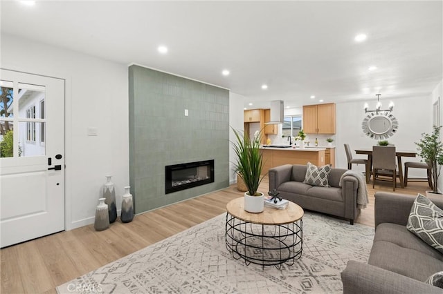 living room with a chandelier, light wood finished floors, a tile fireplace, and recessed lighting