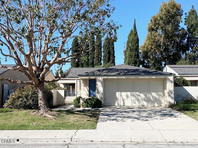 view of front facade with an attached garage, driveway, a gate, and fence