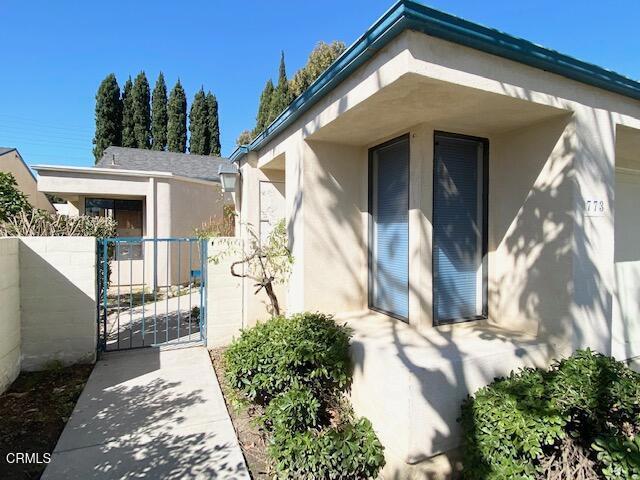 view of exterior entry with fence, a gate, and stucco siding