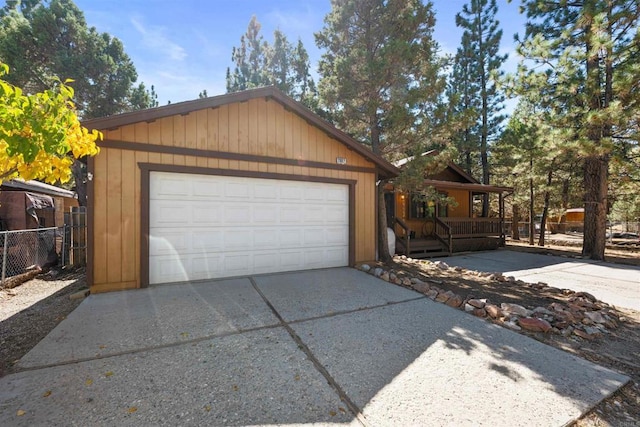 garage with covered porch, fence, and driveway