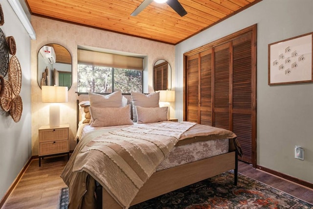 bedroom featuring wooden ceiling, wood finished floors, baseboards, ornamental molding, and a closet