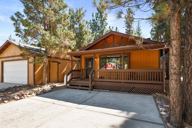 chalet / cabin with a garage, a porch, and an outdoor structure