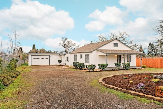 view of front of house featuring driveway, an attached garage, fence, and a porch