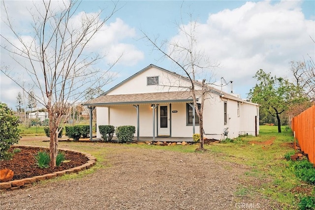 view of front of house with a porch, fence, and stucco siding