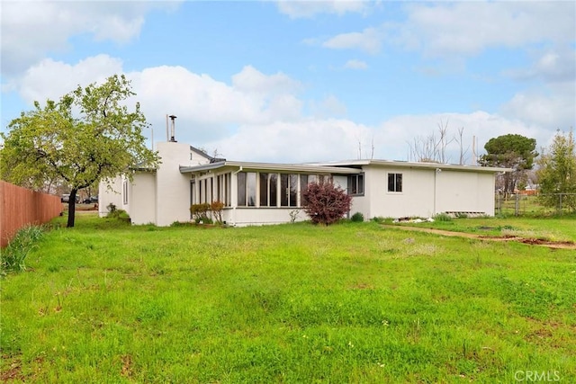 back of house with a sunroom, fence, and a lawn