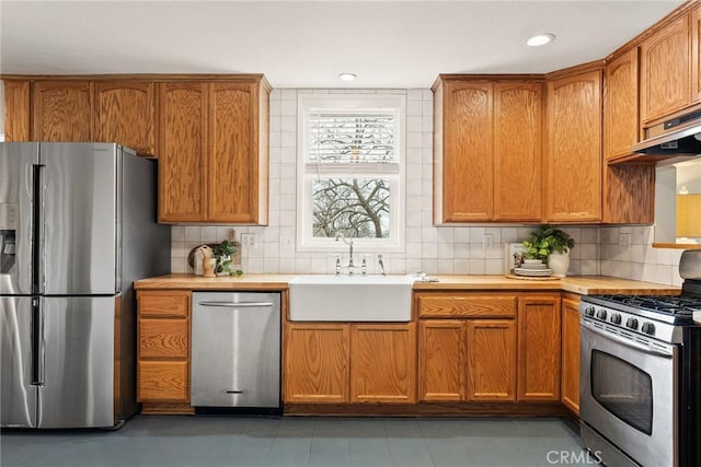 kitchen featuring stainless steel appliances, light countertops, a sink, and tasteful backsplash